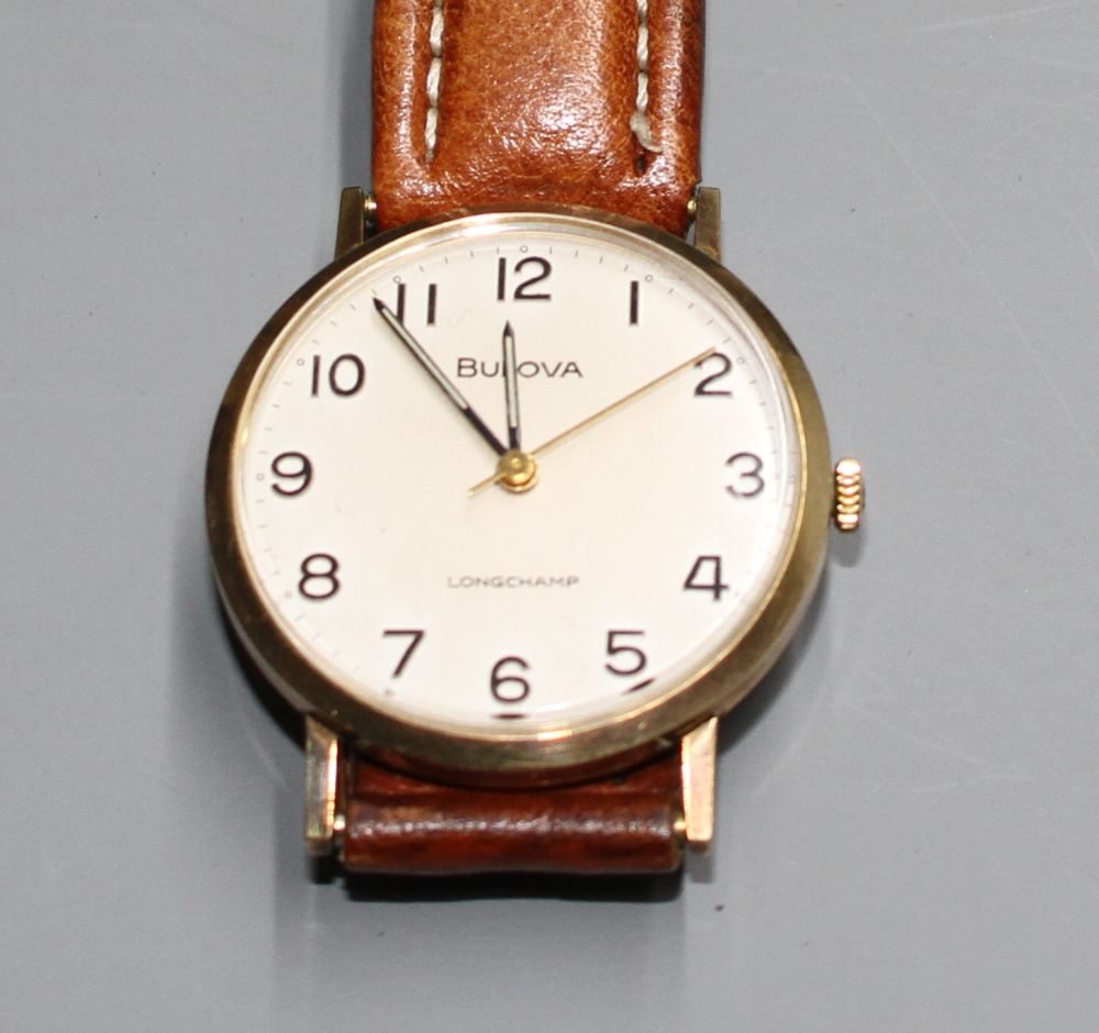 A gentlemans 9ct gold Bulova Longchamp manual wind wrist watch, on associated strap.